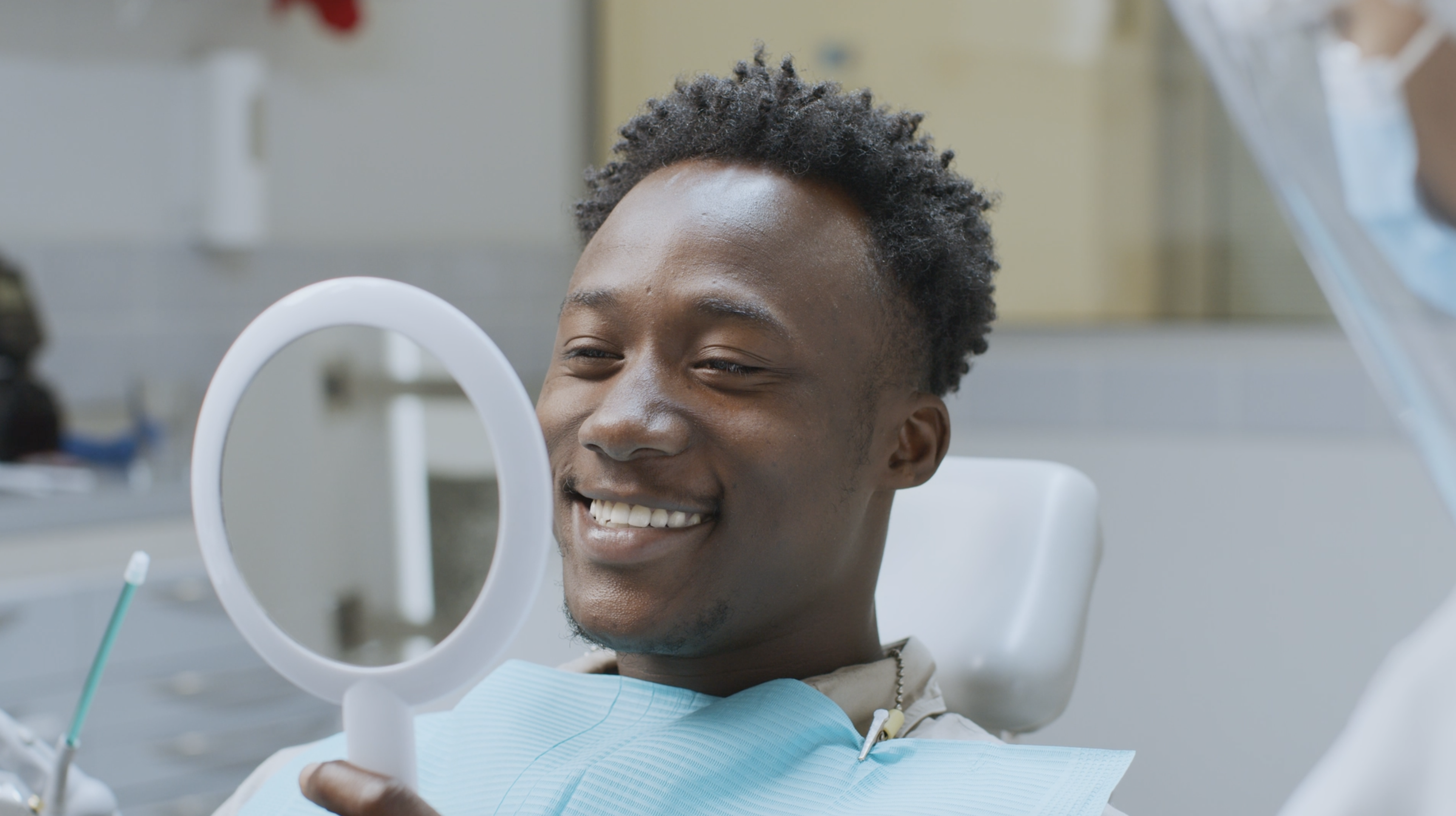 Patient in dental chair viewing teeth in mirror after professional teeth whitening treatment at Rittenhouse Dentists dental office